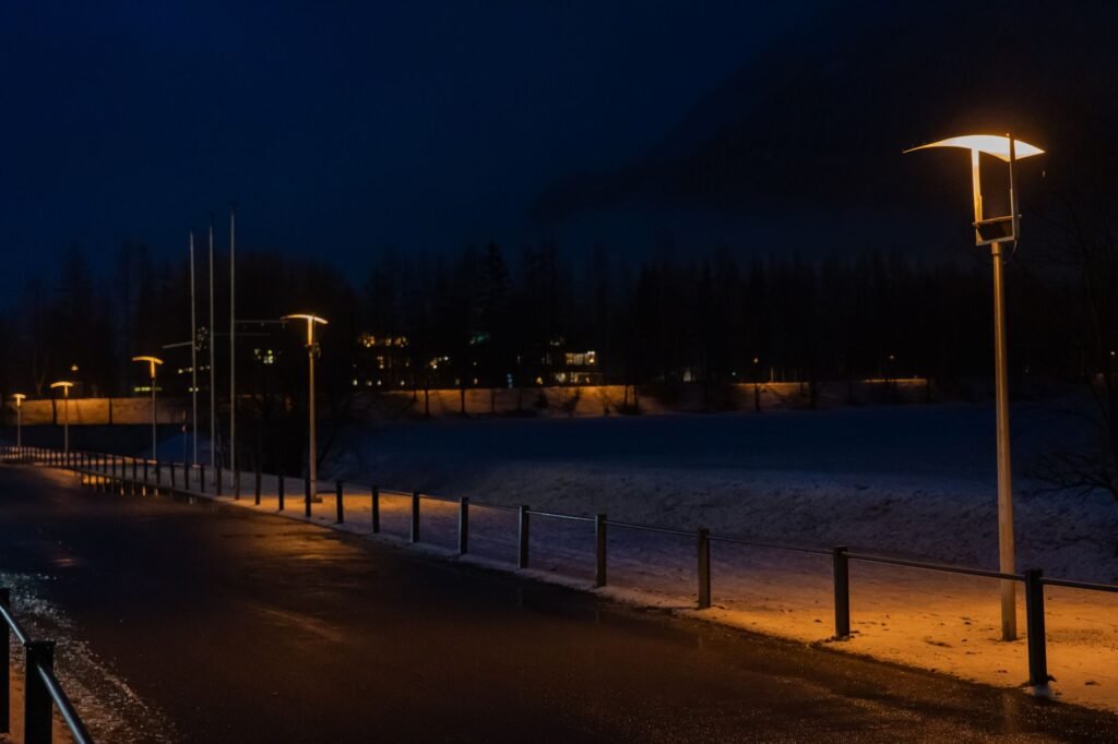 Street light on a road at dusk with illuminated road markings and trees