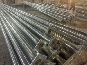Steel lighting poles with welded base plates in a manufacturing workshop