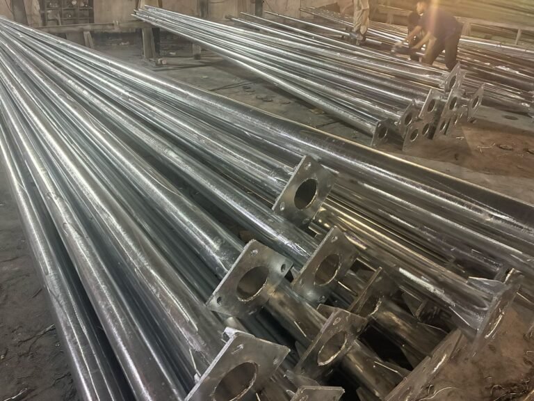 Steel lighting poles with welded base plates in a manufacturing workshop